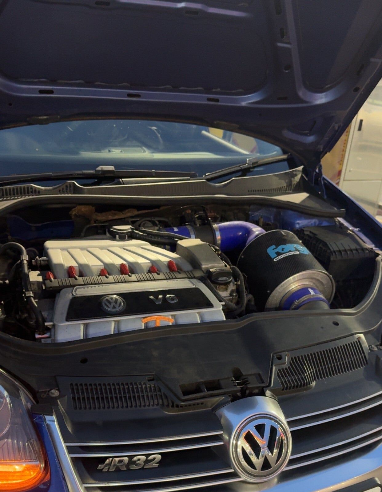 The engine bay of a Volkswagen Golf R32 with the bonnet up, ready for work